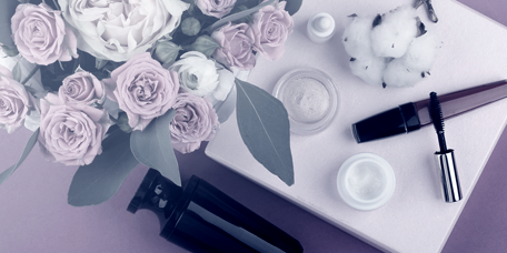 Make-up und Kosmetika neben Blumen abgelegt