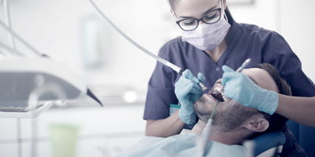 Dentiste en train de procéder à un détartrage sur un patient